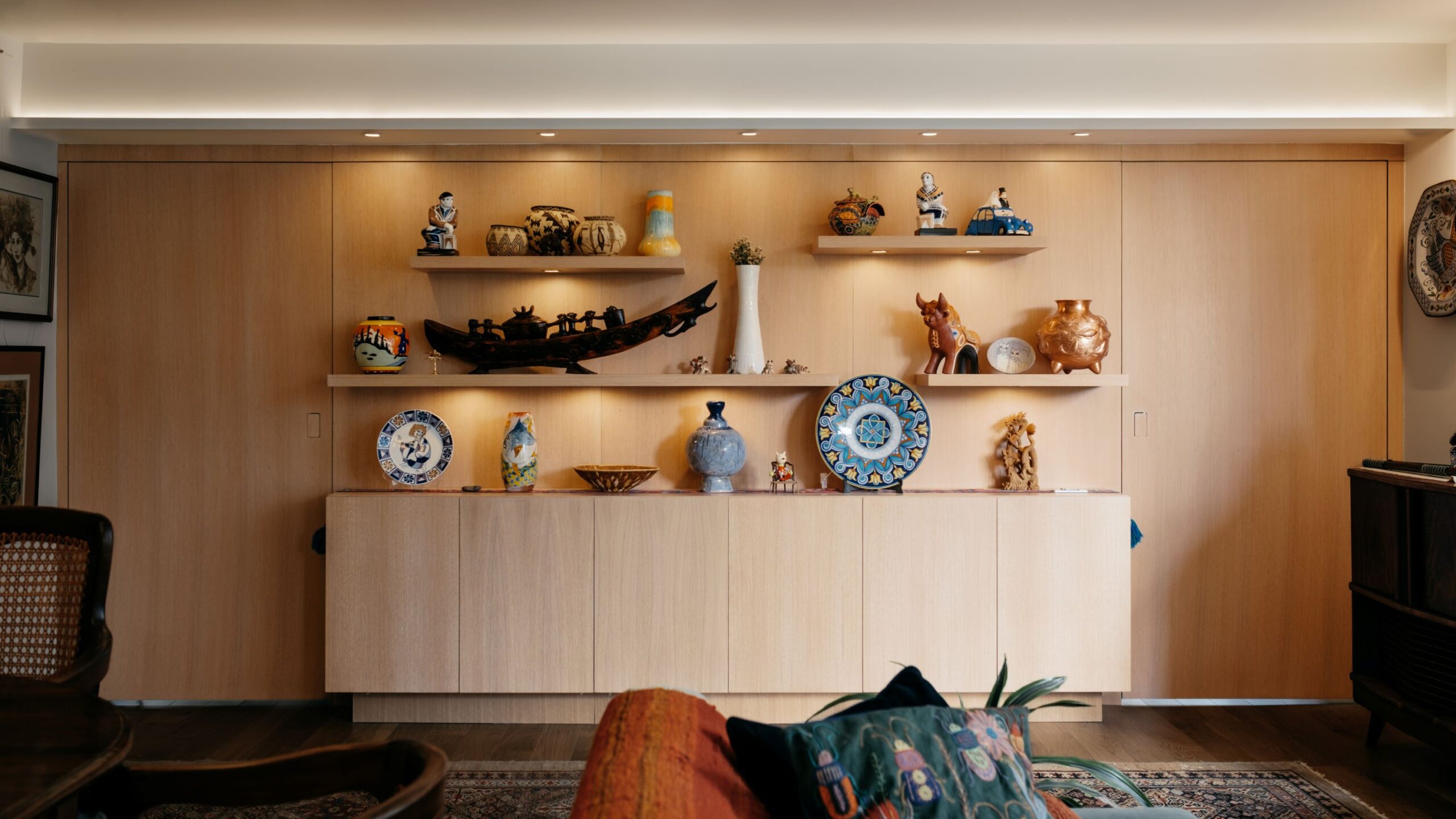 View of eco-friendly home with custom wood display wall complete with hidden doors on either side and cabinet below, with custom LED lighting.